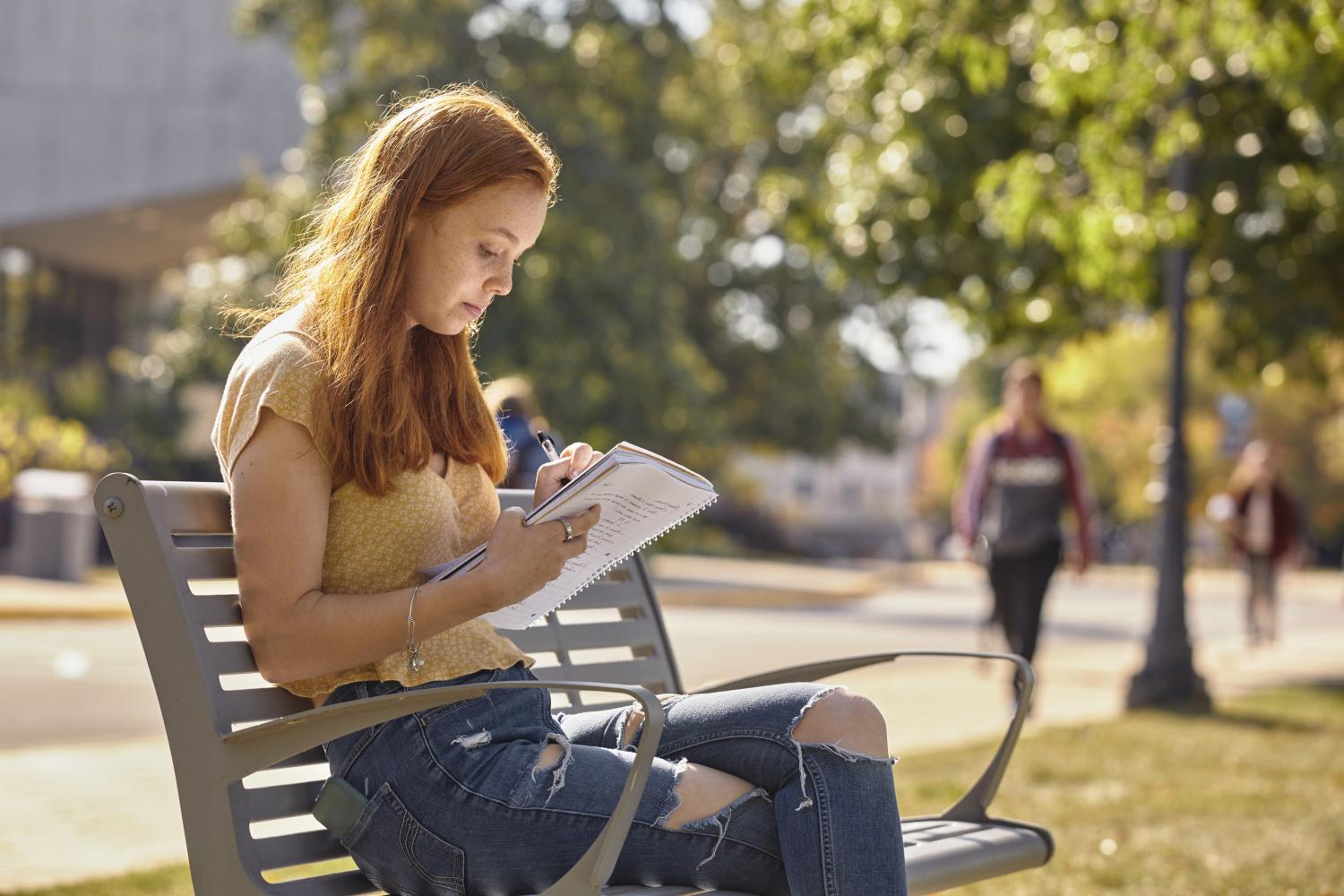 A <a href='http://wy6.feshine.net'>全球十大赌钱排行app</a> student reads on a bench along Campus Drive.